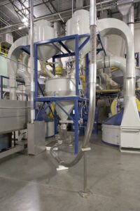 Die frisch gerösteten Kaffeebohnen werden aus den Röstern in einen Trichter geleitet, der sie zum Fördersystem leitet, das sie sanft zu den Lagersilos befördert.