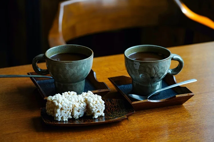 Dos tazas de café y un pastel de arroz.