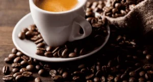 Eine Tasse Kaffee und geröstete Kaffeebohnen drumherum