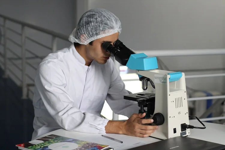 Un hombre en una bata de laboratorio con un microscopio.