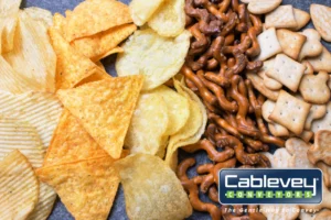 A pile of snacks and a Cablevey Conveyors logo in the bottom right corner
